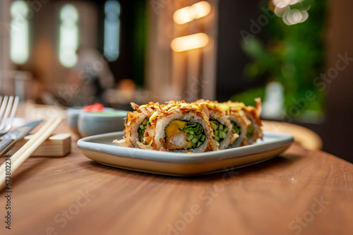 Sushi roll with tuna flakes, tempura shrimp, mango and cucumber on a plate