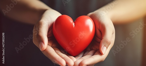 Health care background - Woman hands hold a red heart  illuminated by the sun