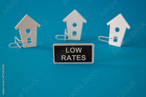 Low house rates symbol. Concept red words Low rates on wooden board near miniature houses. Beautiful blue background  copy space. Business and low house rates concept.