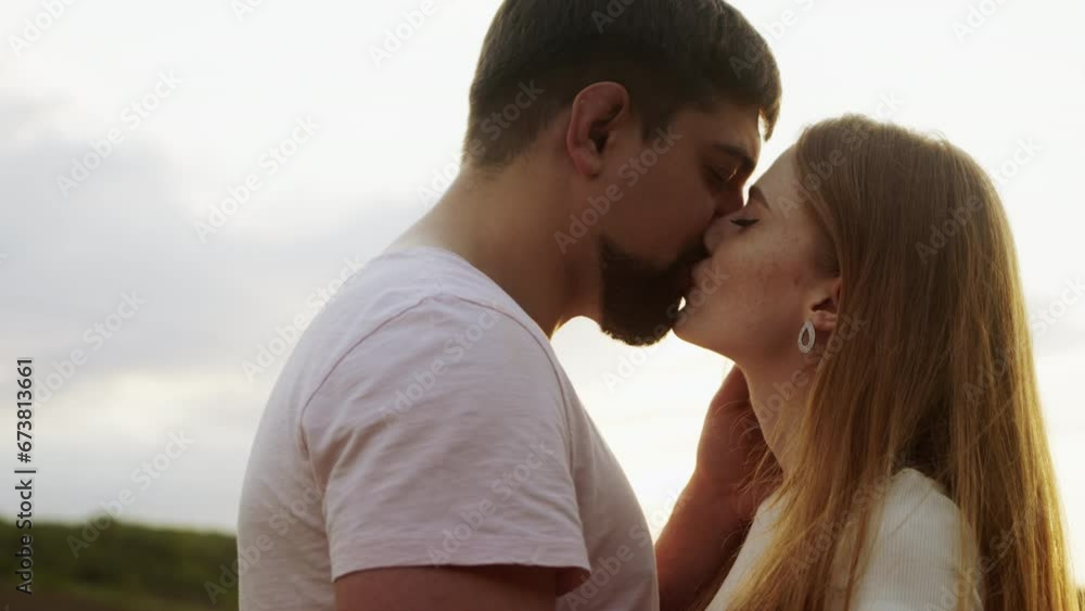 Close-up view of a young caucasian couple passionately kissing while sitting in the middle of a field. Happy people. Female portrait. Romantic date. Woman Close-up view of a young caucasian couple passionately kissing while sitting in the middle of a field. Happy people. Female portrait. Romantic date. Woman