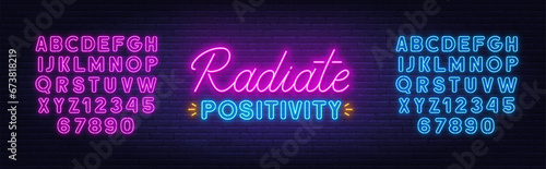 Radiate Positivity neon lettering on brick wall background.