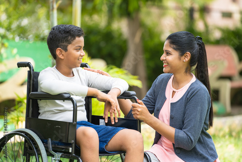 Quadro su tela Happy indian mother playing by cuddling to kid with disability at park - concept