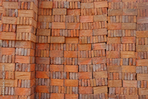 Red brick packed in stacks are stored on ground outdoors at a hardware store warehouse