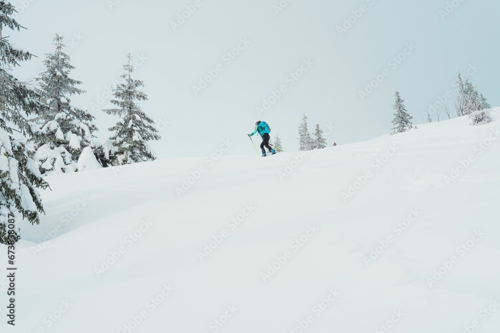 Caucasian man wearing a blue jacket riding down a snowy mountain slope