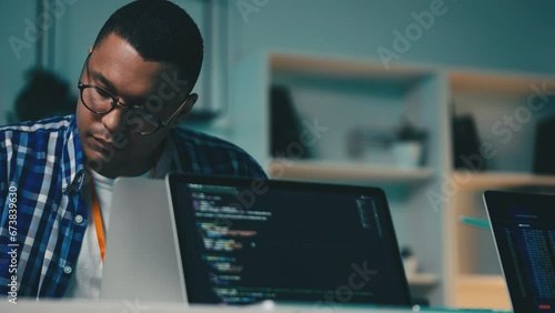 African American software tester checking computer programs on laptop in office photo