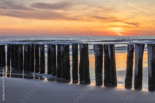 A row of wooden poles on the beach of Schoorl aan Zee, beautifully illuminated by the setting sun. © Bram