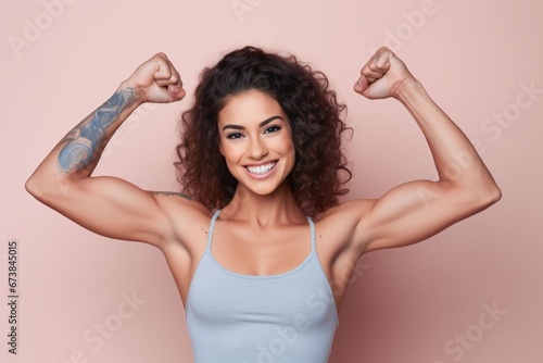 young woman with tattoo on her hand showing her biceps in pastel color studio background photo