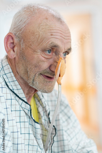 Patient with nasogastric tube on hospital bed waiting for treatment. Positive close up of an elder man waiting for an operation. Enthusiastic approach to hospital treatment. photo
