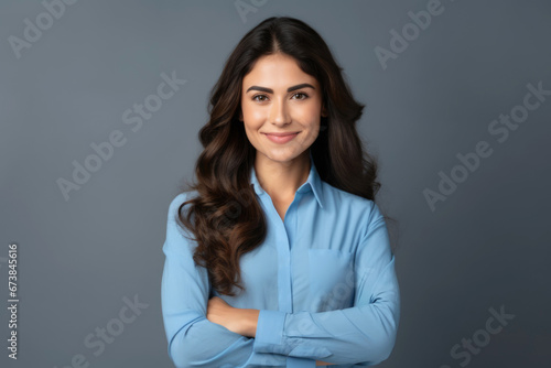 Young smiling corporate shot of business woman standing arms crossed.