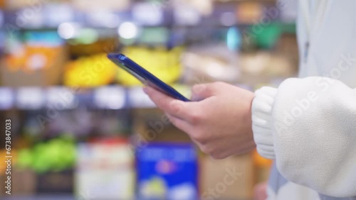 Woman shopping in a supermarket looking at the screen of the phone her shopping list photo