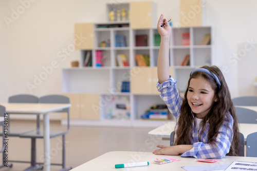 The cute girl raising her hand in rder to be asked photo