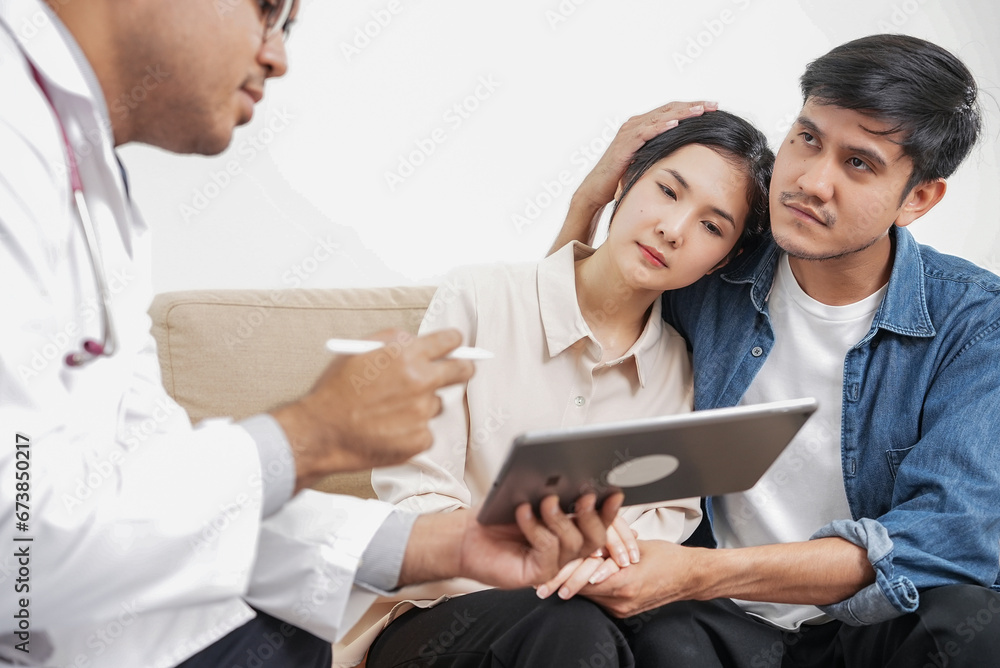 Male doctor giving test result to asian couple patient with tablet. They feeling stressed after received bad news from the doctor in medical office, hospital, clinic or home. Male doctor giving test result to asian couple patient with tablet. They feeling stressed after received bad news from the doctor in medical office, hospital, clinic or home.