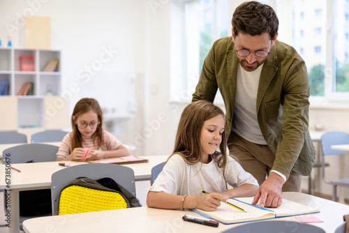 Male teacher helping pupils while writing the test