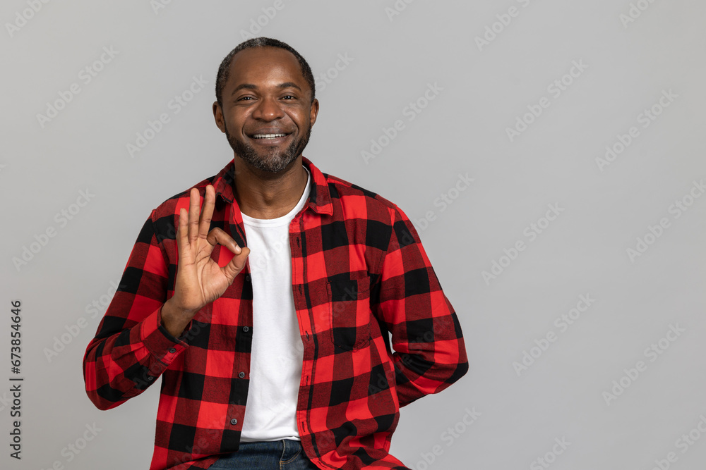 Smiling black bearded man wearing red checkered shirt showing ok sign Smiling black bearded man wearing red checkered shirt showing ok sign