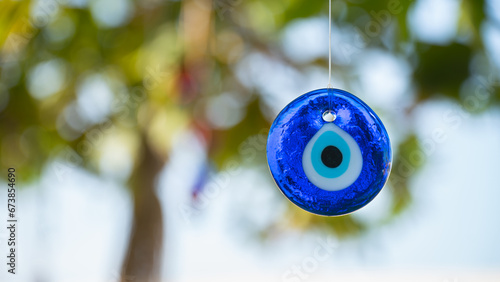The evil eye souvenie hanging on the tree. Blue stone amulet in form of eye to protect from evil people. Popular in Greece, Turkey and Eastern countries  photo