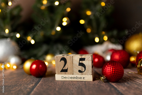 Old vintage wooden calendar for the date of Christmas December 25 against the background of New Year's lights of garlands of bokeh light bulbs photo
