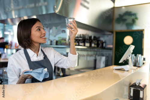 Dark-haired coffee shop assistant cleaning glasses and smiling © zinkevych