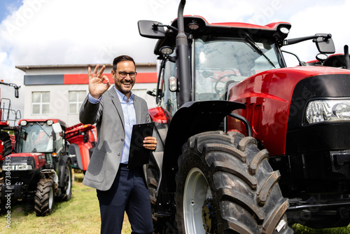 Salesman in business suit selling tractors and farming equipment.