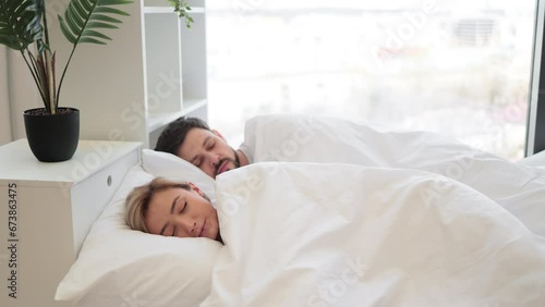 Young caucasian family of two in casual clothing having deep dream before awaking early in morning. Romantic partners sharing relationship closeness by sleeping on same sides under one blanket.