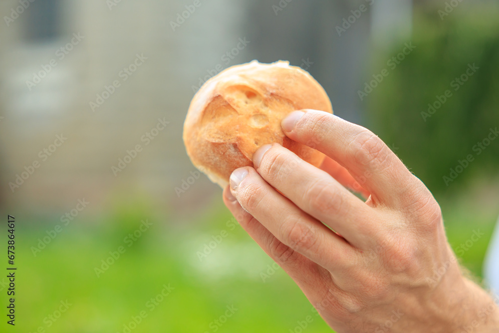 Guy's hand holds a round bun, snack and fast food concept. Selective focus on hands with blurred background
