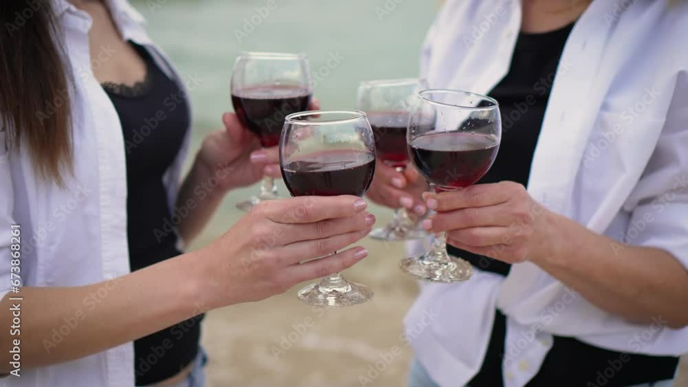 Two cheerful women hold out glasses of red wine to person outside frame close up. Having picnic on summer evening Two cheerful women hold out glasses of red wine to person outside frame close up. Having picnic on summer evening