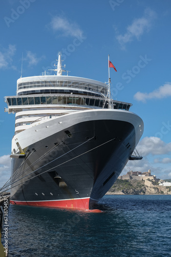 Classic british luxury ocean liner cruiseship cruise ship in port with detail view of steel hull, bow, superstructure and bridge in black, white and red color paint photo