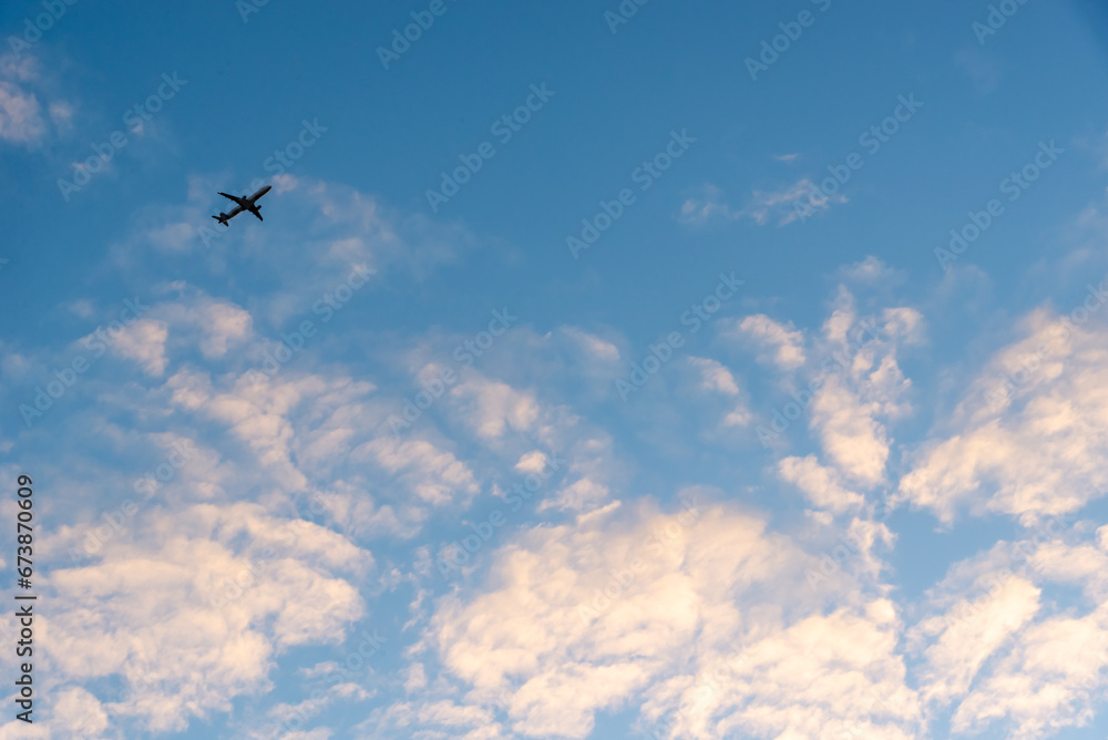 Fototapeta premium Airplane flying on blue sky with clouds.