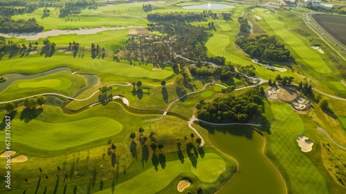 green golf course surrounded by wooded landscape and a pond at a distance