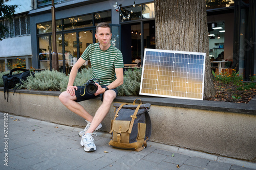 Traveling photographer using solar panel to charge his camera. photo