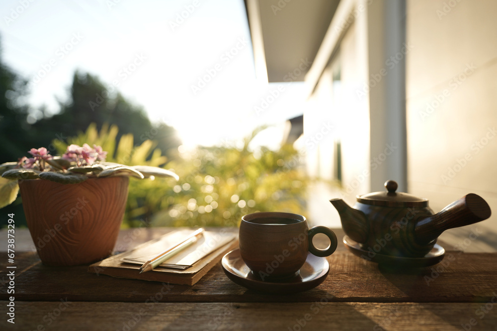 Earthenware tea cup and tea pot with brown plant pot and notebooks Earthenware tea cup and tea pot with brown plant pot and notebooks