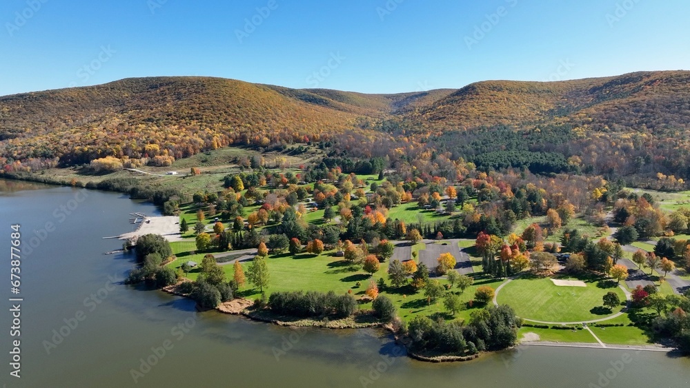 Camping in the great outdoors in nature in campgrounds for RVs and tents on a green pastures below a mountain range in Autumn Fall colors in Ives Run Campground in Pennsylvania countryside