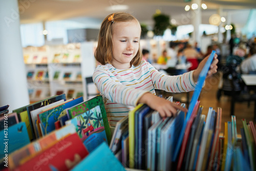 Five year old girl selecting a book in municipal library photo