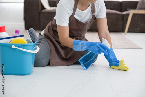 Woman scrubbing floor using spray and sponge cloth.