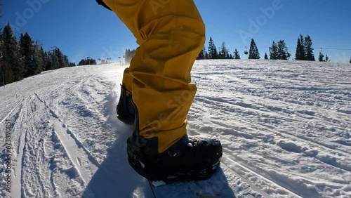 SLO MO Freestyle snowboarder having fun on the ski resort ,making curves in slow motion. Sun peaking from behind. photo