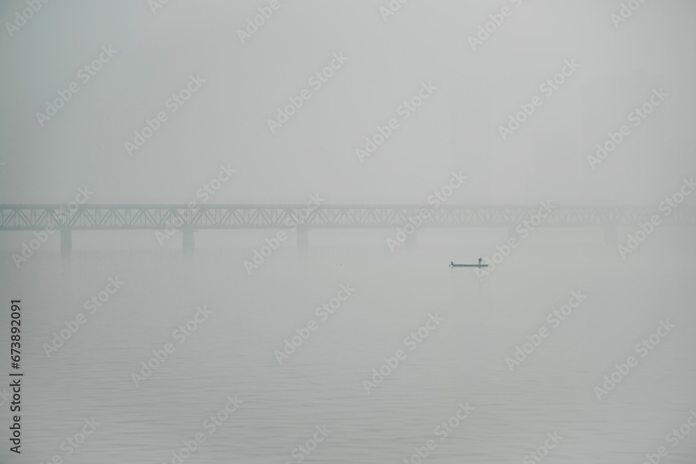 Bridge and a small boat on a wide river on a foggy day in Hangzhou, Zhejiang, China