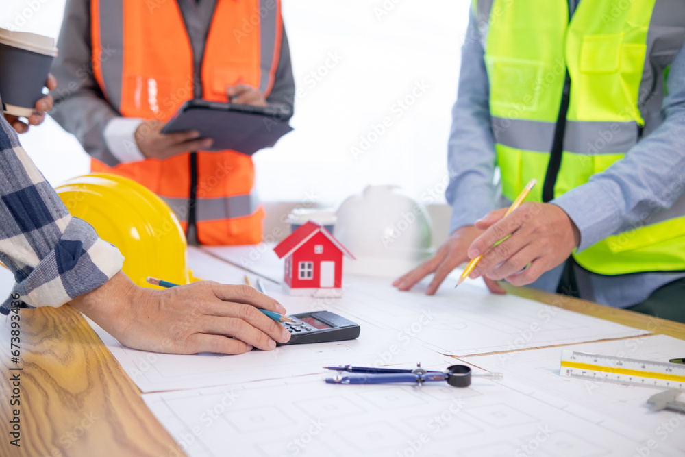 Architects and construction engineers meet to discuss blueprints of building structures in order to calculate the completion of the construction project. Real estate construction business concept. Architects and construction engineers meet to discuss blueprints of building structures in order to calculate the completion of the construction project. Real estate construction business concept.