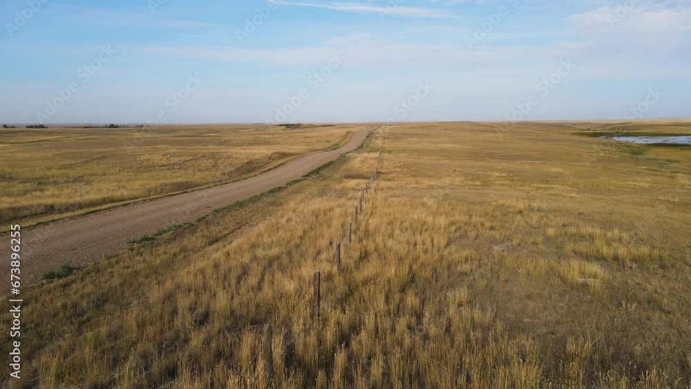 Drone flying low above a dry western American landscape. The path of the drone follows a barbed wire fence next to a gravel road. The blue sky has thin white clouds.
Drone flying low above a dry western American landscape. The path of the drone follows a barbed wire fence next to a gravel road. The blue sky has thin white clouds.