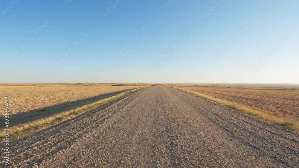 POV from the front of a vehicle driving along a gravel road through open prairie in the fall. The truck slows to cross a Texas cattle gate. The sky is blue with hazy white clouds.
POV from the front of a vehicle driving along a gravel road through open prairie in the fall. The truck slows to cross a Texas cattle gate. The sky is blue with hazy white clouds.
