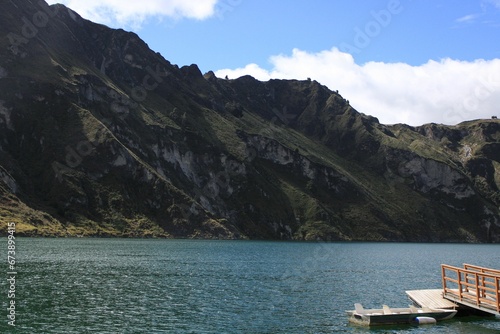 Small boat secured to a wooden dock on a tranquil lake  with a stunning mountain backdrop