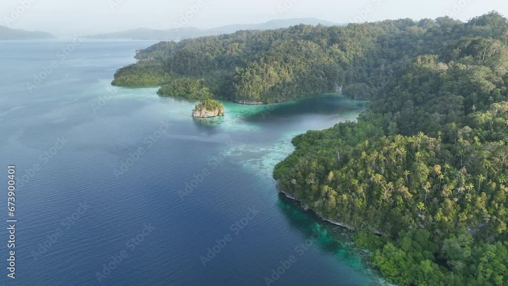Rugged, jungle-covered islands are fringed by reefs in the calm waters of Alyui Bay, Raja Ampat. This scenic area is known as the heart of the Coral Triangle due to its incredible marine biodiversity. Rugged, jungle-covered islands are fringed by reefs in the calm waters of Alyui Bay, Raja Ampat. This scenic area is known as the heart of the Coral Triangle due to its incredible marine biodiversity.