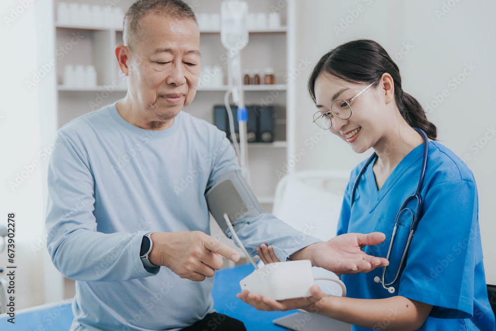 Obraz premium Beautiful Asian female nurse in a nursing uniform talks to a senior patient at the bedside in a hospital or clinic department.