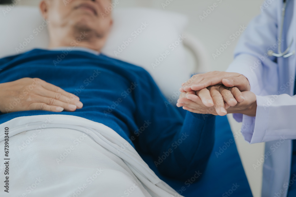 Beautiful Asian female doctor in white top talking with senior patient at bedside in hospital or clinic ward Beautiful Asian female doctor in white top talking with senior patient at bedside in hospital or clinic ward