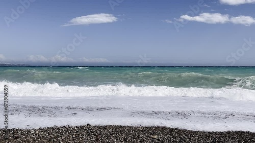 Powerful sea waves are crashing on coast. Waves splash on the beach with pebbles during a storm. Storm at sea.