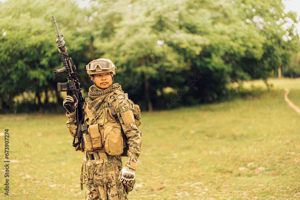 A combat expert soldier stands in the forest holding a rifle ready to fire, looking around, wearing vision goggles. and camouflage uniforms To fight with enemies in the dangerous battlefields of war.