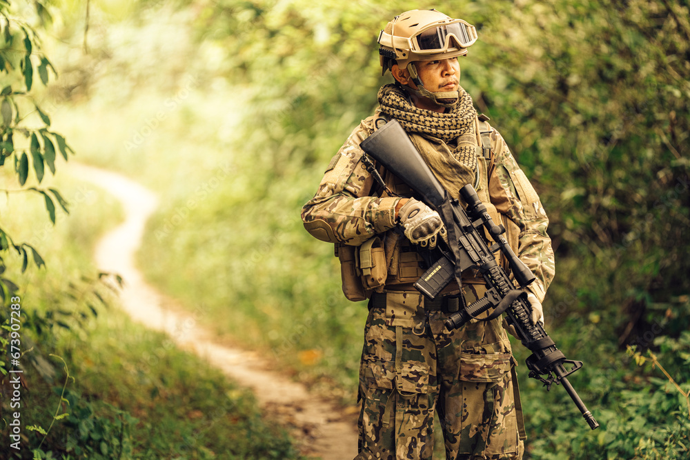 Military experts stand patrolling in the forest, carrying rifles, bags, vision goggles, and wearing camouflage uniforms. Ready to fight with the enemy in the dangerous battlefield of war.