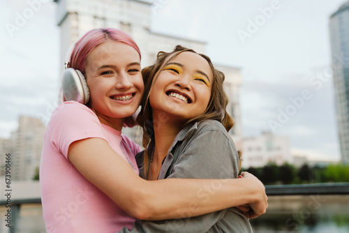 Two smiling girls hugging while standing at city street photo