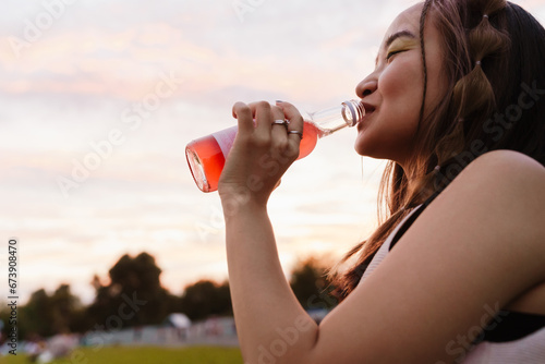 Portrait of beautiful girl drinking lemonade while standing in park photo