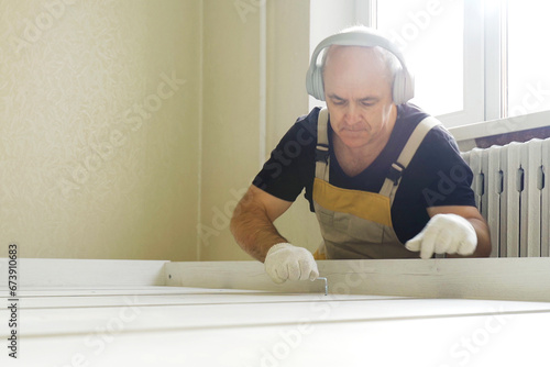 A worker fastens the parts of a bed using a confirmat. photo