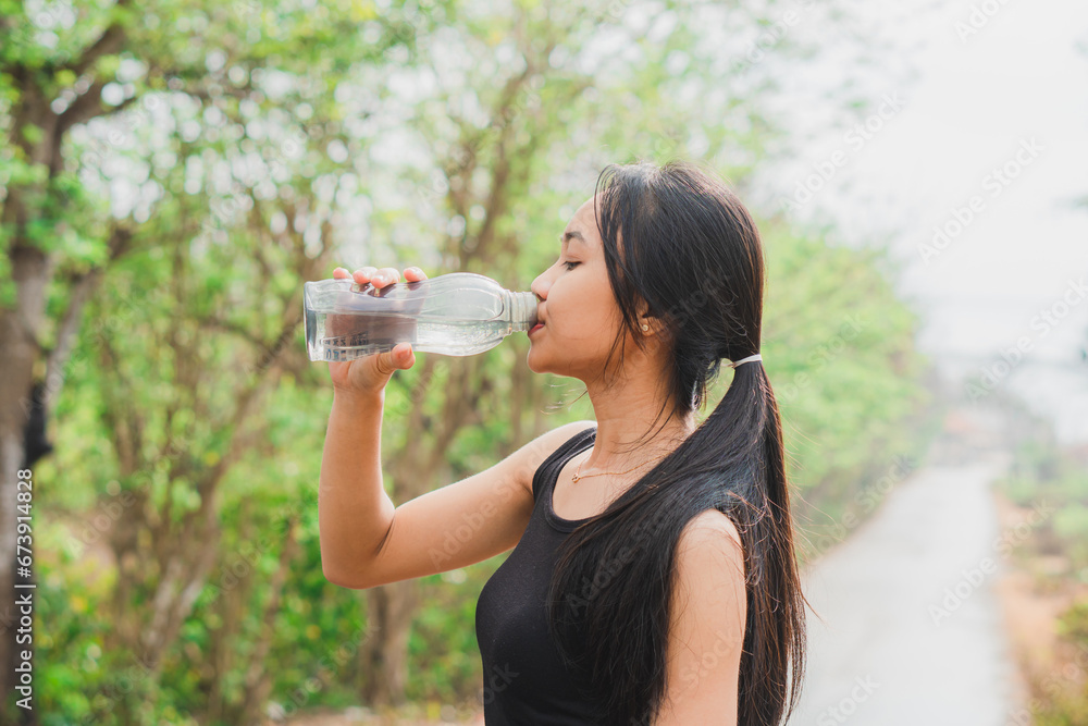 Female jogger drinking water in the street Female jogger drinking water in the street