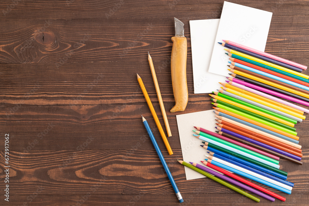 Obraz premium Set of watercolor pencils on brown wooden. Top view, copy space